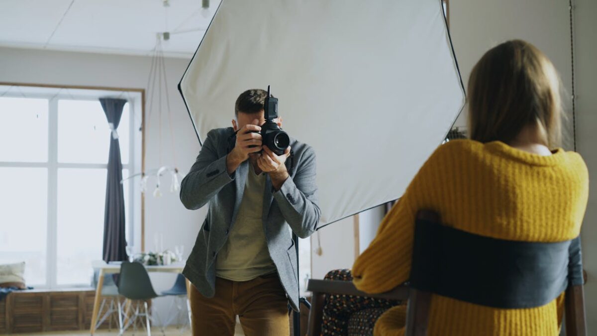 A photographer taking a portrait shot in an indoor studio with natural light.